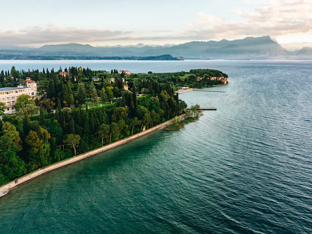 Weitläufige Aussicht über den Gardasee mit üppigen Zypressen und malerischer Küstenlinie