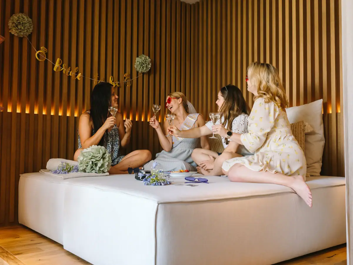 Braut und Freundinnen feiern entspannt bei Sekt und Snacks in einer SPA-Suite im A-ROSA Gardasee.