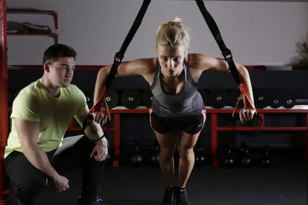 Training Eine Frau hebt ein TRX-Band in einem Fitnessstudio.