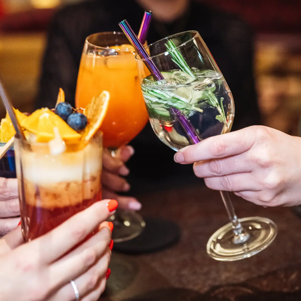 Eine Gruppe von Händen hält Gläser mit Cocktails.