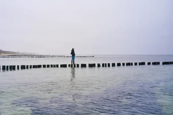 Eine Person steht auf einem Baumstamm im Wasser.