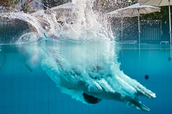 Eine Person taucht in einen Pool.