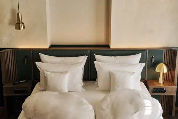 Ein Bett mit weißen Kissen und einem grünen Kopfteil.