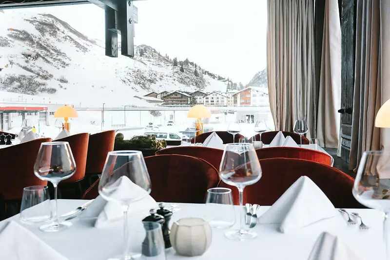 Ein gedeckter Tisch im Thurnher’s Restaurant mit Blick auf schneebedeckte Berge.