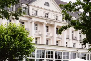 Weißes Gebäude mit Bäumen im Hintergrund
