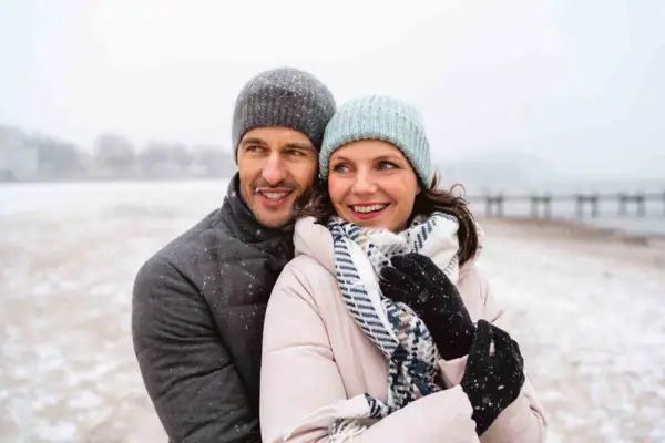 Ein Mann und eine Frau in Winterkleidung lächeln im Freien.