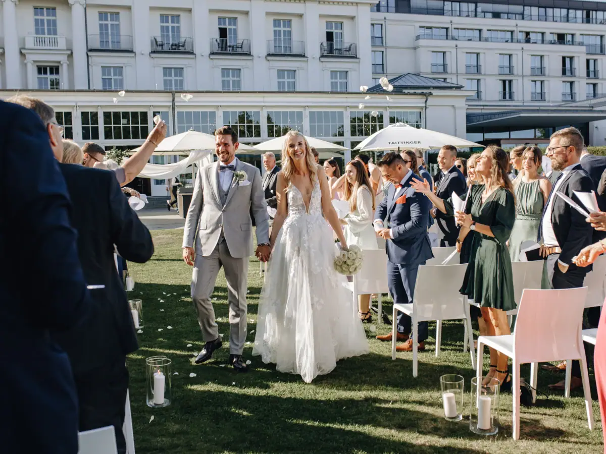 Ein Mann und eine Frau im Hochzeitskleid gehen über einen Rasen.