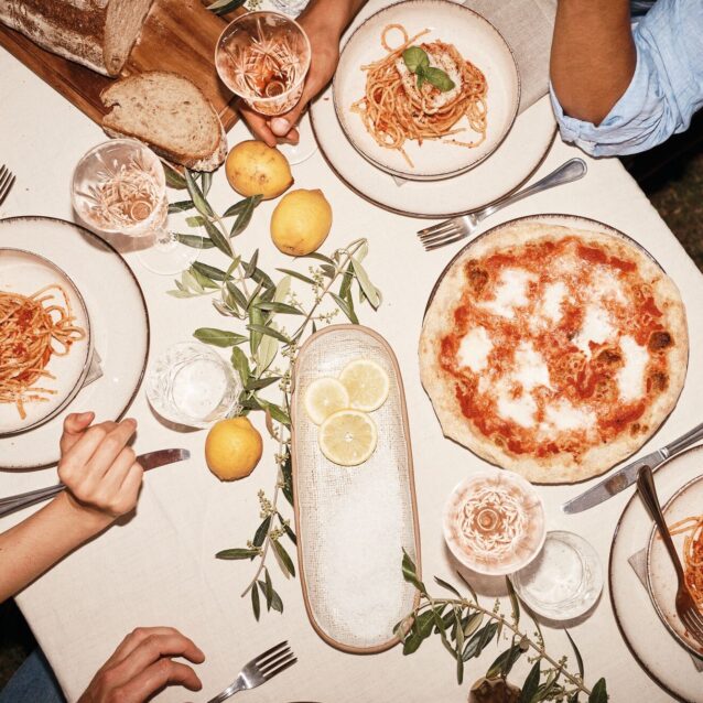 Blick auf einen sorgfältig gedeckten Tisch mit Pastagerichten und Pizza von oben