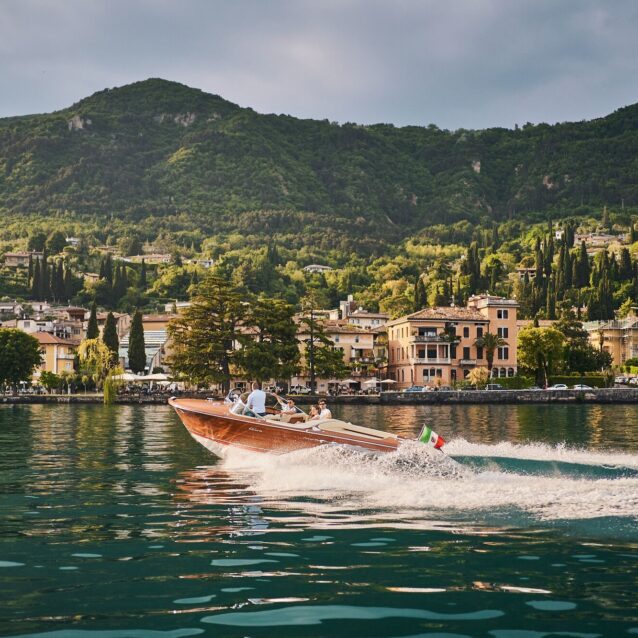 Motorboot fährt über das blaue Wasser und am Ufer liegt die Stadt Salo
