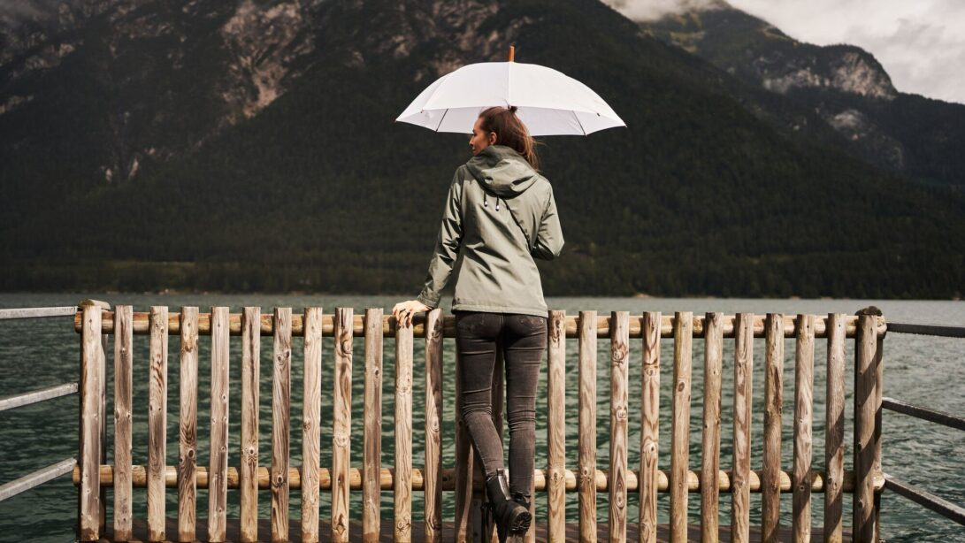 Frau mit Regenschirm steht am Achensee