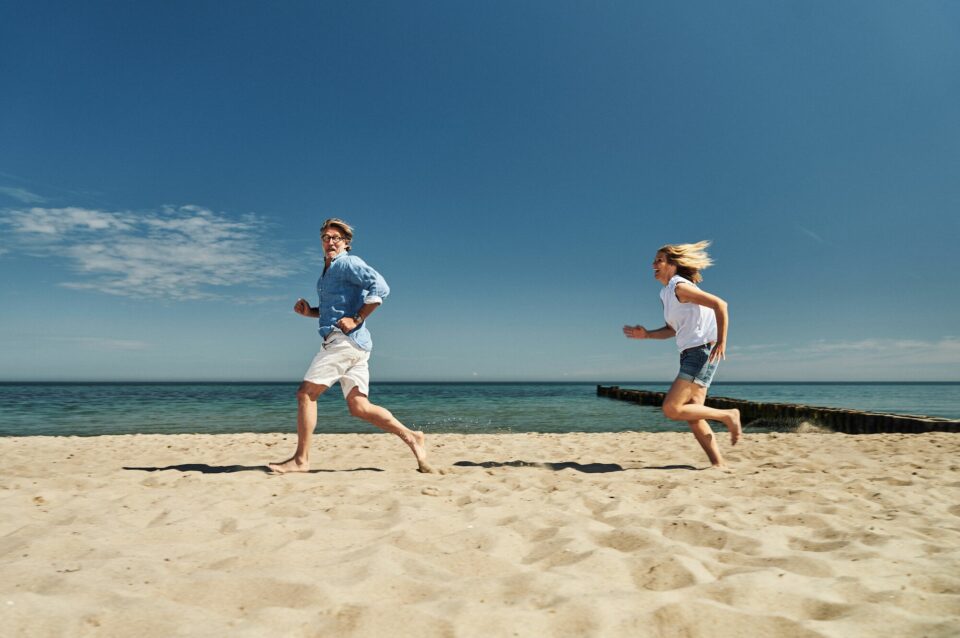Eine Frau rennt freudig einem Mann am Strand in Kühlungsborn hinterher