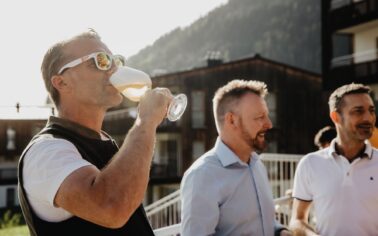 Mann trinkt Bier aus Bierglas mit Stil in Gesellschaft auf Terrasse