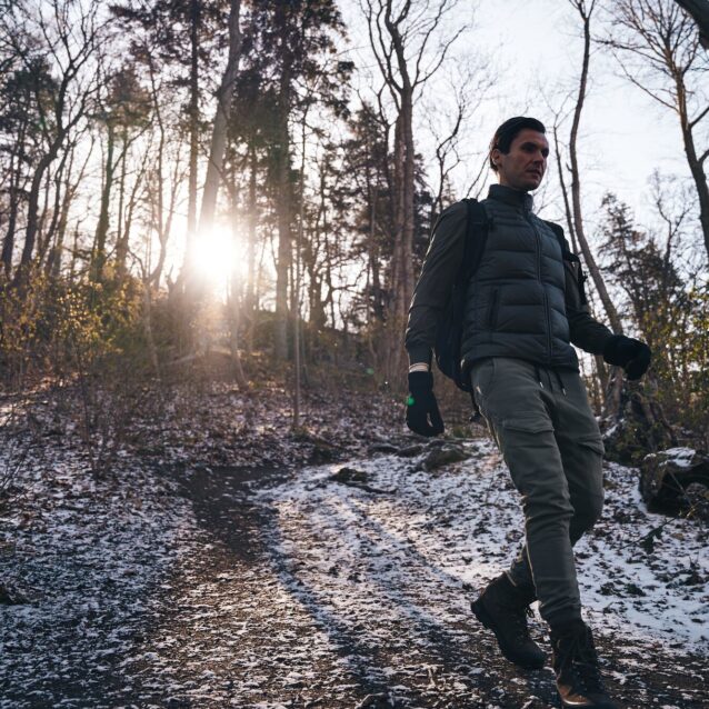Ein Mann in in winterlicher Kleidung wandert mit Rucksack auf dem Rück durch einen Wald im Harz