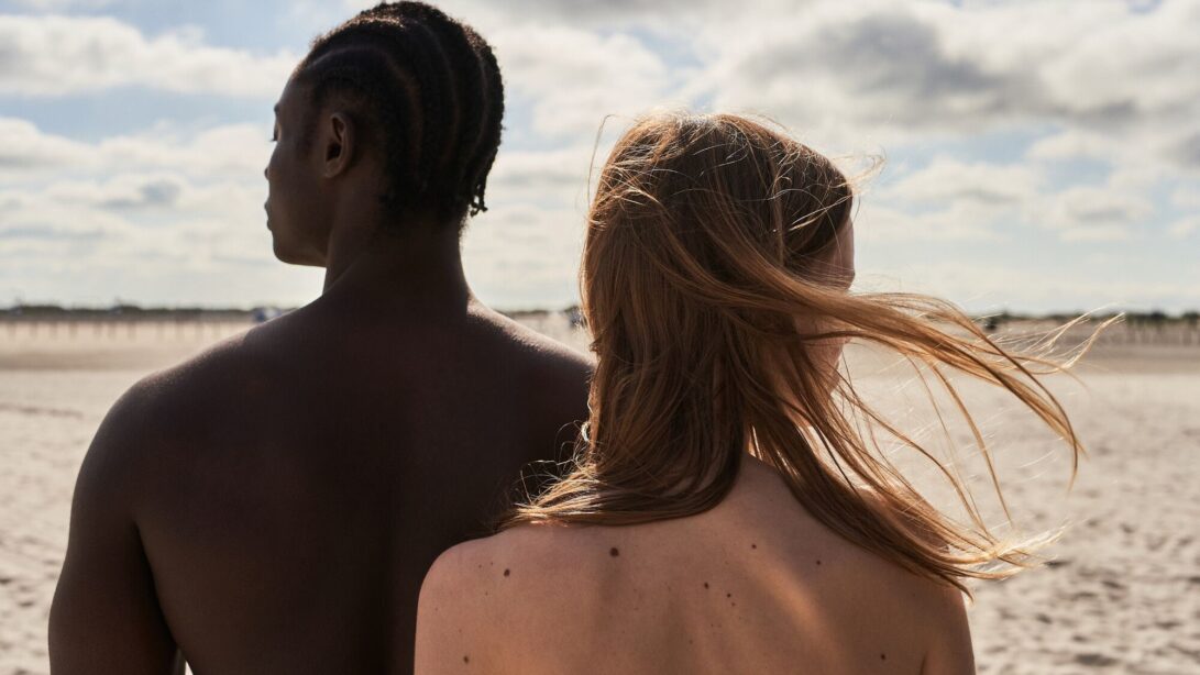 Mann und Frau sind mit nacktem Rücken an einem Strand zu sehen