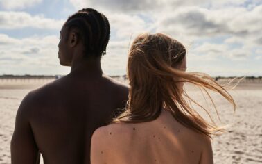Mann und Frau sind mit nacktem Rücken an einem Strand zu sehen