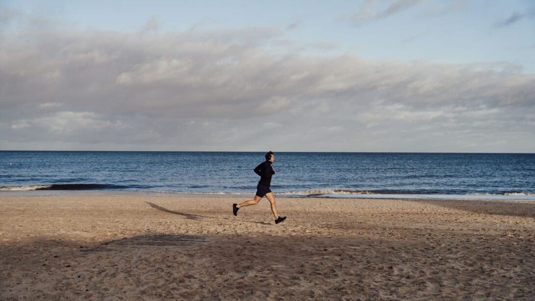 Ein Jogger läuft am Strand am Meer entlang.