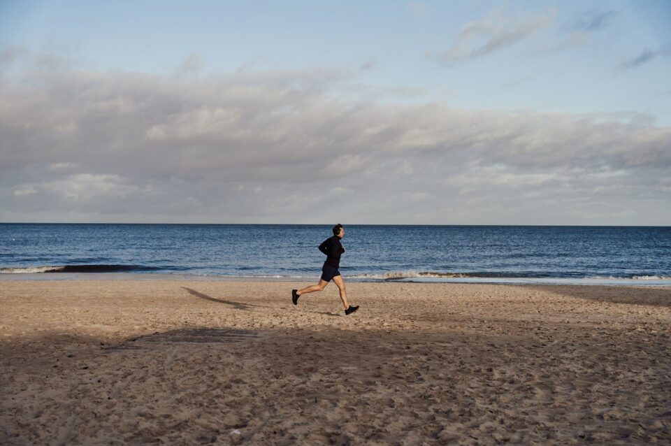 Ein Jogger läuft am Strand am Meer entlang.