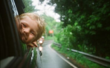 Kind guckt aus geöffnetem Autofenster nach vorne